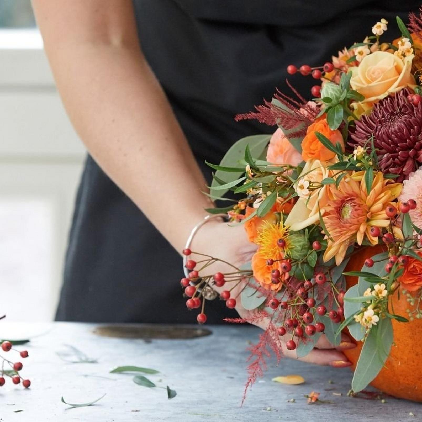 florist-adding-finishing-touch-to-pumpkin-arrangement