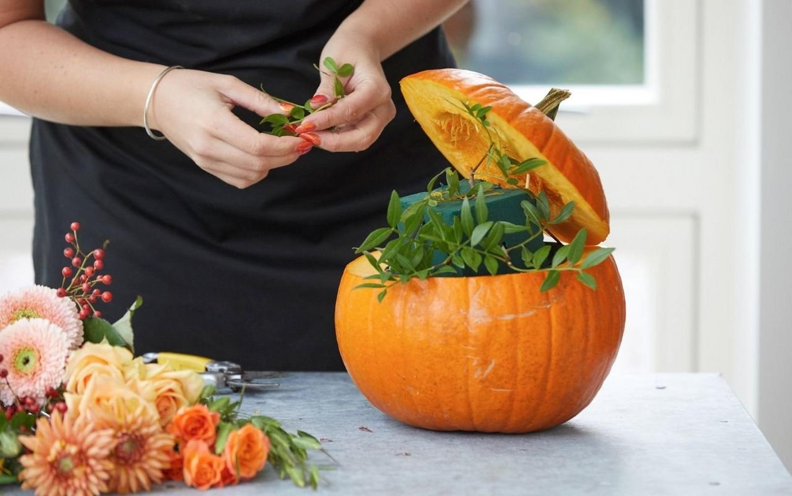 florist-adding-foliage-to-pumpkin-arrangement