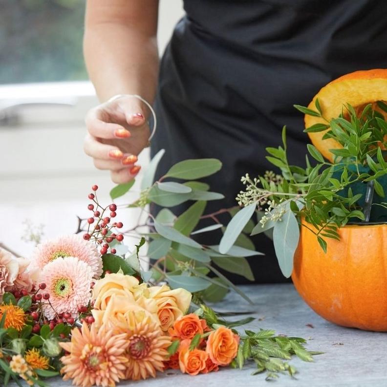 florist-arranging-foliage-in-pumpkin-arrangement