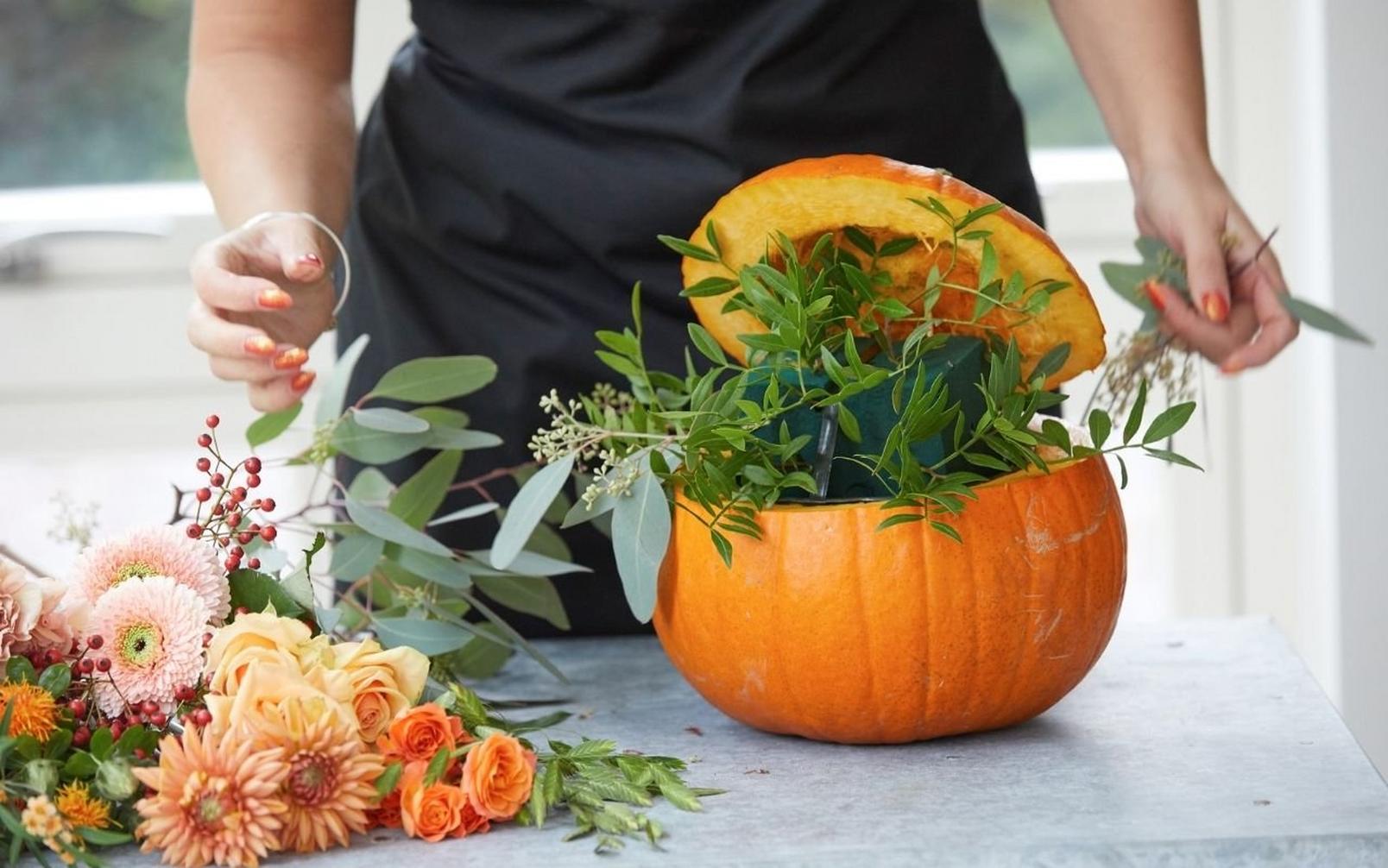 florist-arranging-foliage-in-pumpkin-arrangement